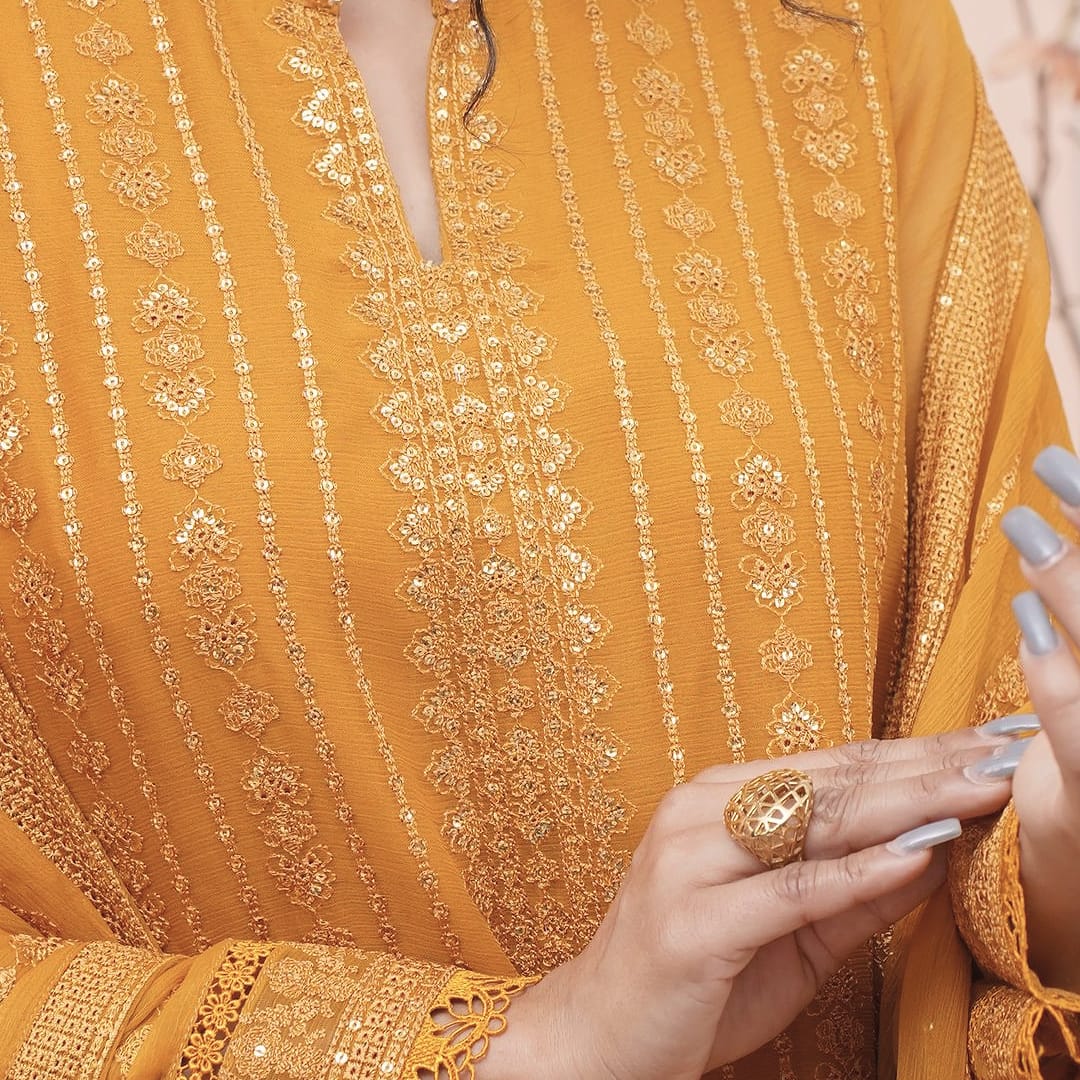 A close detail of a saffron-mustard long coat-front kurta set: the gold-thread striped placket.