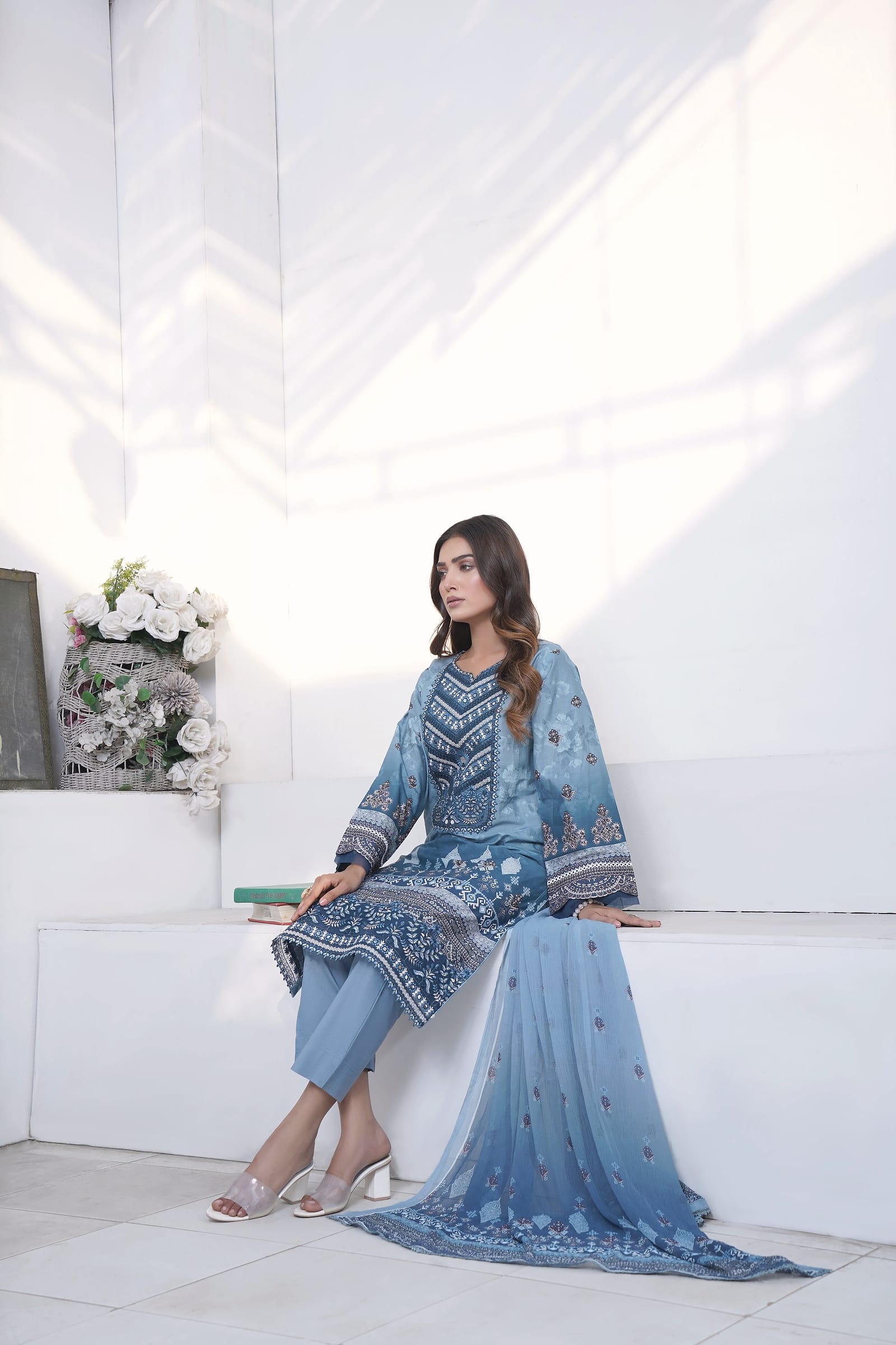 A woman sits in a white room, wearing a sky-blue ombre kurta set with a navy chevron yoke.