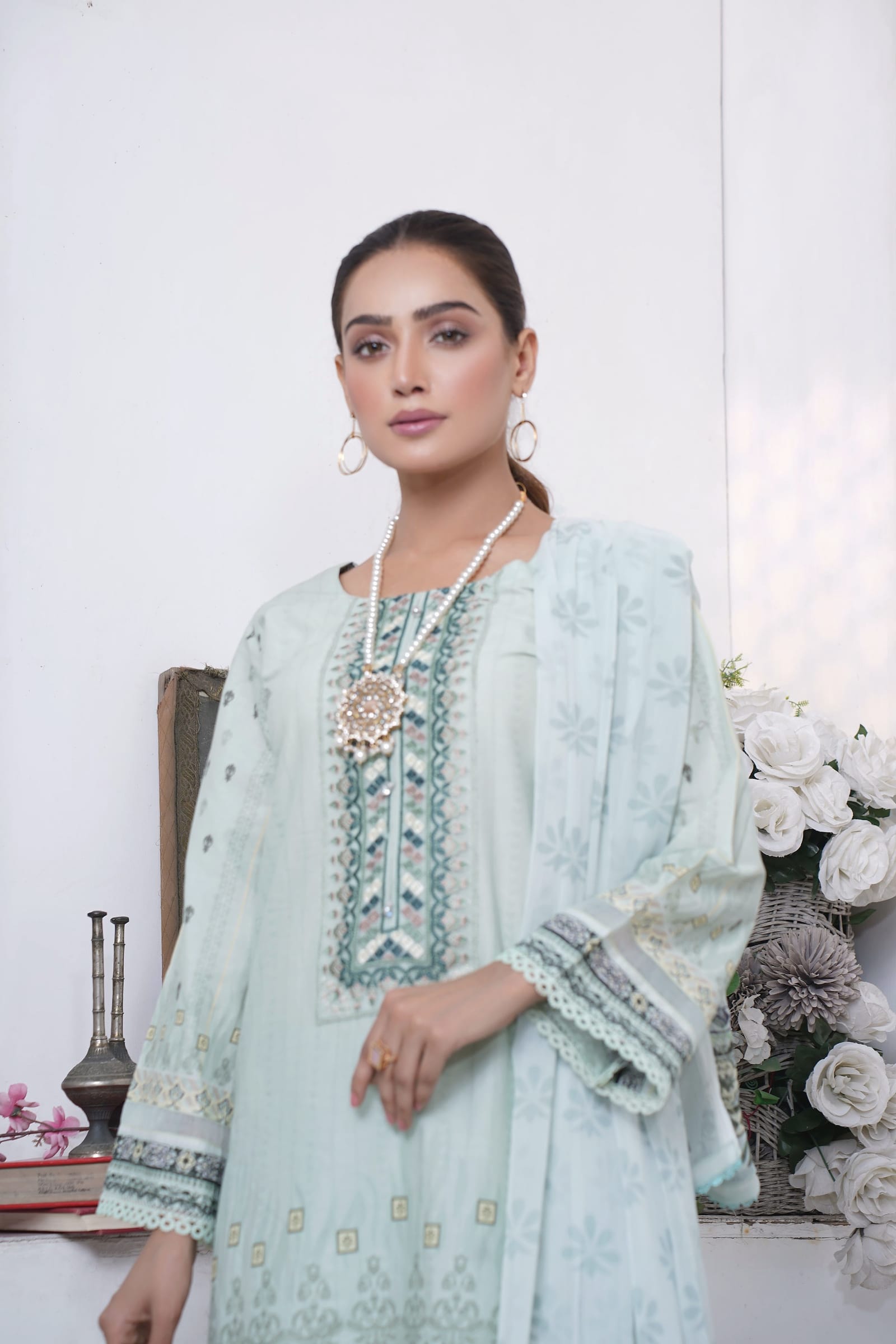 A woman is close, showing the yoke and a pearl and gold necklace, wearing a pale mint kurta set with an aqua and grey embroidered yoke and a long dupatta.