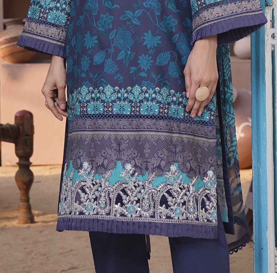 A close detail of an ink-navy kurta set with an aqua floral print and a wave-print dupatta: the aqua paisley hem band and pleated edge.