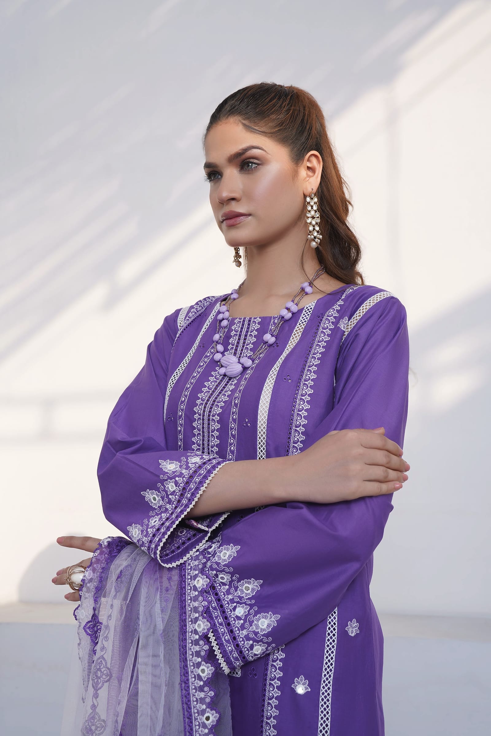 A woman is close, showing the lace-edged cuff, wearing a violet kurta set with white lace and cuff embroidery and a net dupatta.
